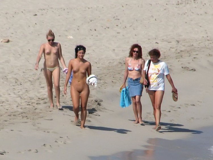 Nudists walk along the beach