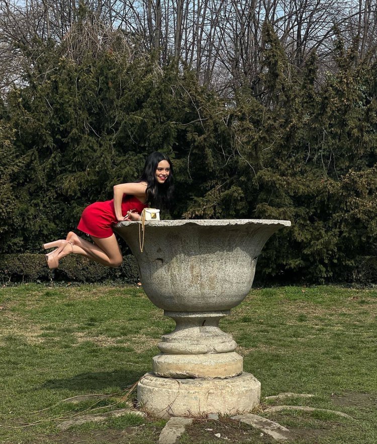 Jenna Ortega sits on the grass