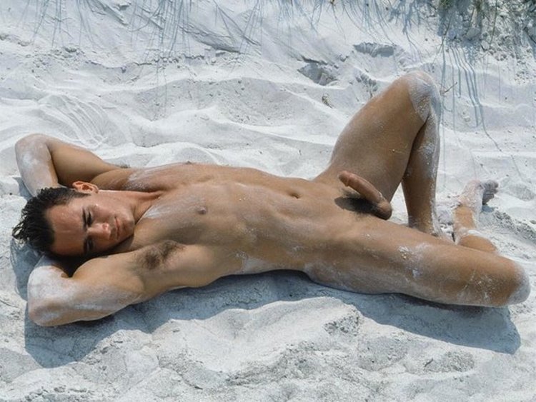A naked man lies on the beach