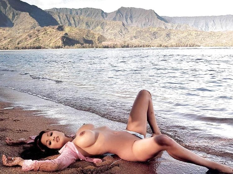 A naked woman lies on the seashore