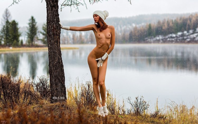 The girl undresses on the riverbank